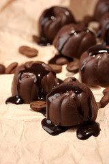 Chocolate candies and coffee beans, on beige paper background