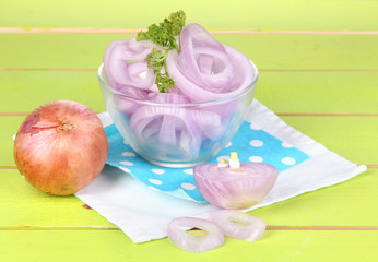 Onion cut with rings in bowl on wooden table close-up