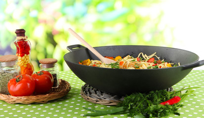 Noodles with vegetables on wok on nature background