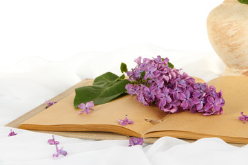 Lilacs branch on book on white fabric background