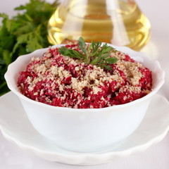Beet salad with walnuts in a white bowl, close up