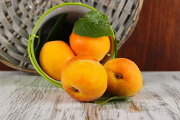 Apricots in bucket on wooden table near wicker coasters