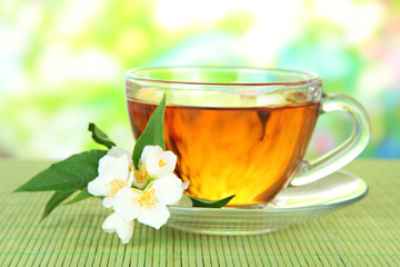 Cup of tea with jasmine, on bamboo mat, on bright background