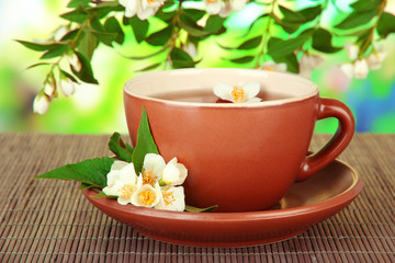 Cup of tea with jasmine, on bamboo mat, on bright background