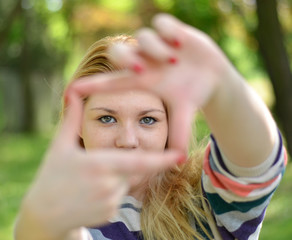 Fototapeta premium Beautiful girl making frame with hands while outdoors