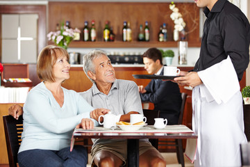 Kellner bedient Senioren im Café