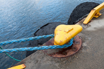 Yellow mooring bollard with blue naval rope