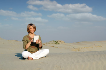 happy woman play with tablet pc in desert