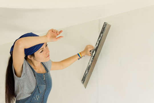 Tired woman wallpapering a wall