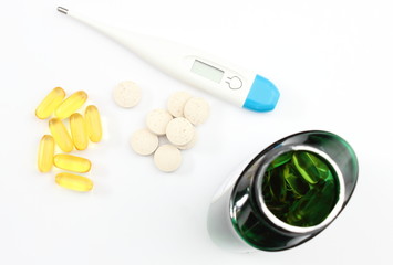 Thermometer with pills on white background