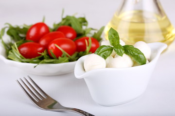 mozzarella mini, tomatoes and fresh basil leaves in white bowl