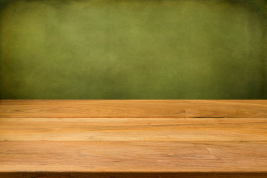 Empty wooden table over grunge green background