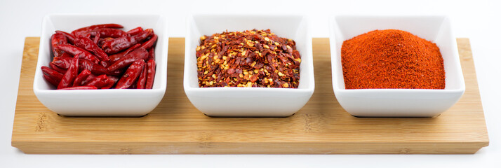 Whole chili peppers, flakes, and chili powder isolated on white