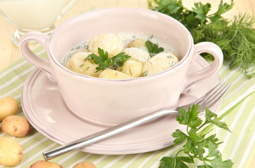 Tender young potatoes with sour cream and herbs in pan