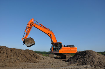 Excavator at work in open sand mine and a blue sky