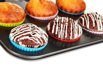 Tasty muffin cakes in baking tray isolated on white