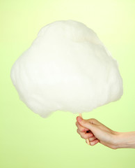 Hand holding stick with cotton candy, on color background