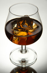 Brandy glass with ice on grey background