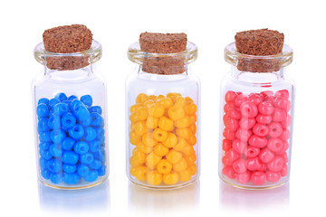 Different colorful beads in bottles isolated on white
