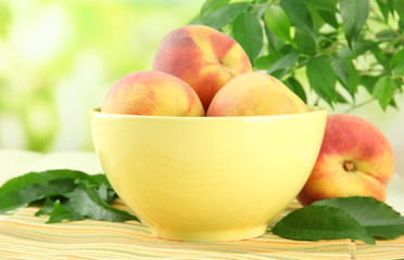 Ripe sweet peaches on table in bowl, outdoors