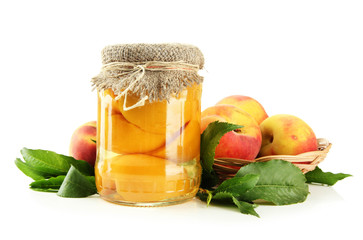 Jar of canned peaches and fresh peaches, isolated on white