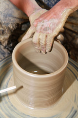 Close-up of hands making pottery on pottery wheel