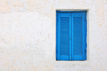 Fototapeta na wymiar Biała fasada domu z niebieskimi okiennicami w Pyrgos