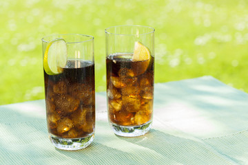Cold cola soda in sunlight summer garden
