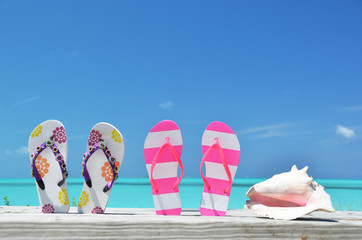 Two pairs of flip-flops against ocean. Exuma, Bahamas