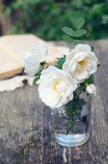 Dog rose flowers in a glass on rusted wooden table