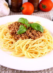 Delicious spaghetti bolognese with basil leaves on white plate