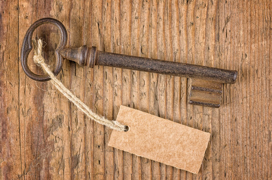 Alter Schlüssel mit Anhänger auf einem Holzbrett