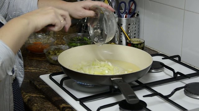 Housewife puts onions in the pan