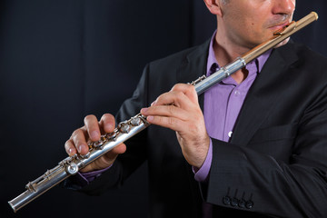 professional flutist musician playing flute on black background © Mediteraneo