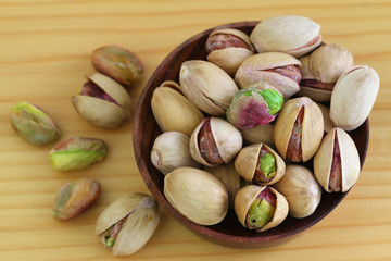 Pistachio nuts with and without shell on wooden surface