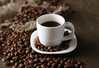 Cup of coffee and coffee beans on wooden background