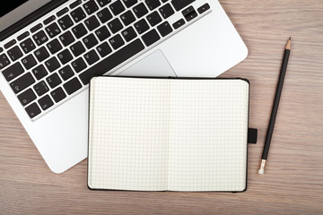 Notepad and laptop on wood table