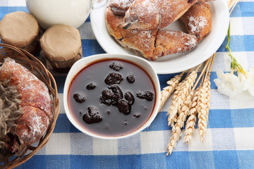 Taste croissants, milk and jam, on tablecloth.