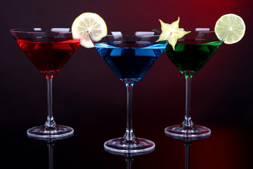 Alcoholic cocktails in martini glasses on dark red background