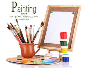 Small easel with sheet of paper and art supplies isolated