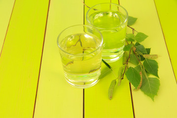 Glasses of birch sap on green wooden table