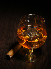 Brandy glass with ice on wooden background