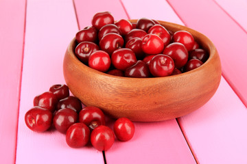 Cherry berries in bowl on wooden table close-up