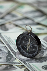 Closeup of a compass placed on U.S. Dollar banknotes