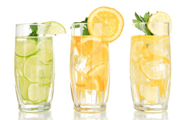 Glasses of fruit drinks with ice cubes isolated on white