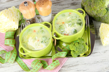 Cabbage soup in plates on metal tray on napkin on wooden table