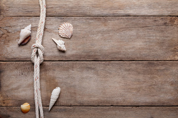 Weathered wooden table background with rope reef knot and shells