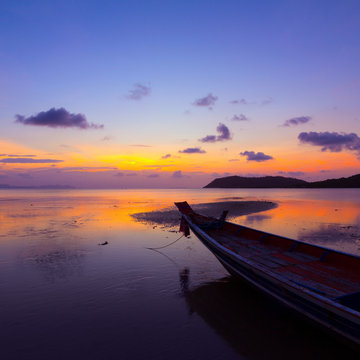 Sunset over sea with small wooden boat, Thailand
