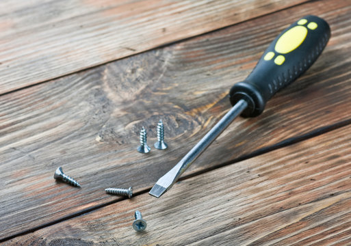 screwdriver and screws on a wooden table