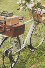 Naklejka premium Vintage bicycle on the field with a basket of flowers